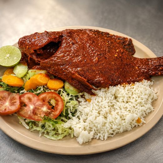 Pescado entero cubierto de salsa roja, servido con arroz blanco y ensalada de lechuga, jitomate y zanahoria
