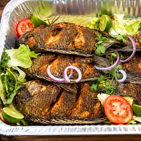 Charola de mojarras fritas doradas sobre lechuga, con jitomate, limón y cebolla morada